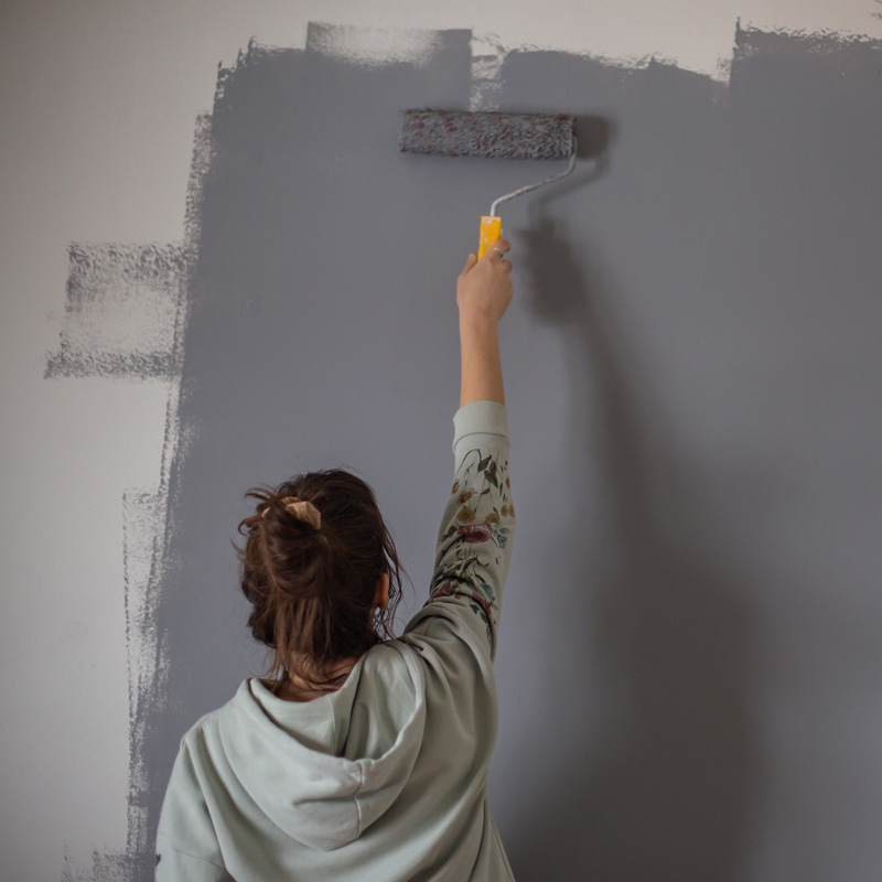 lady using a paint roller on a wall
